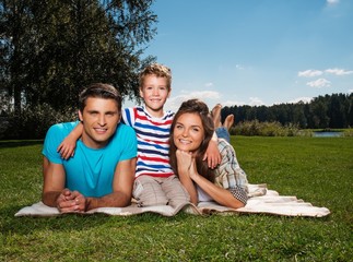 Young family with their child lying on a blanket outdoors