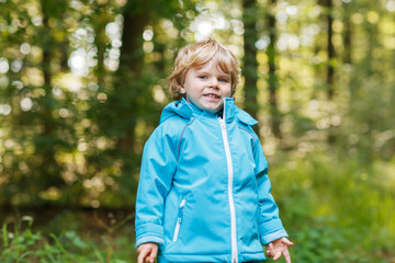 Portrait of blond little toddler  boy in blue waterproof raincoa