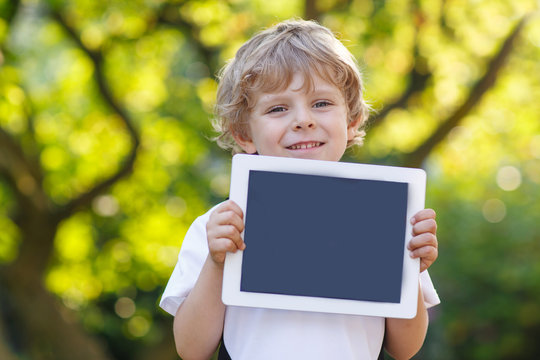 Smiling happy little child holding tablet pc, outdoors