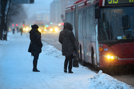 Commuters waiting for arriving bus in snowstorm