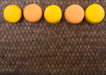 Yellow and orange colored French macarons on wicker background