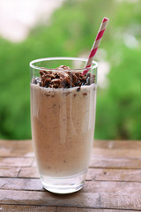 Milk cocktail in glass on table on natural background