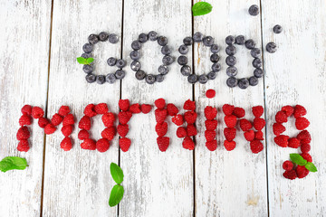 Words put on wooden background with blueberries and raspberries