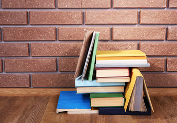 Books on wooden table on brick wall background