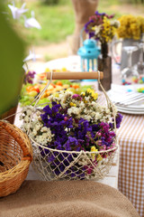 Fototapeta na wymiar Basket with flowers on table, outdoors
