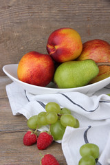 Naklejka na ściany i meble ripe fruits in bowl on wooden background