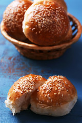 Tasty buns with sesame in wicker basket,