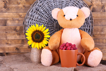 Toy bear and mug of raspberries and flowers