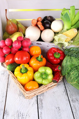 Vegetables in crate and in basket on white wooden box
