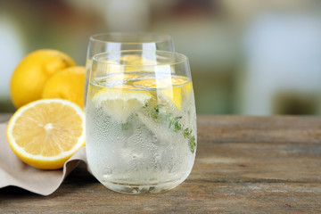Tasty cool beverage with lemon and thyme, on light background