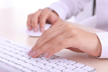 Female hands typing on keyboard on light background