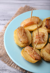 Baked potato with bacon on plate, on wooden background