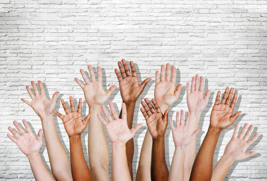 Group of Human Arms Raised with Brick Wall
