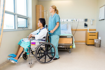 Obraz premium Nurse With Patient Sitting On Wheel Chair At Hospital Window