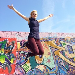 Mädchen macht Luftsprung vor Mauer