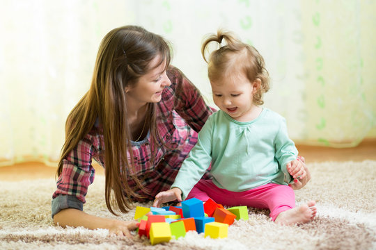 Happy mother and kid play with toys at home