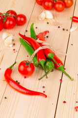 Hot peppers with tomatoes on wood.