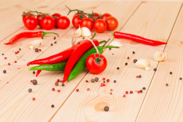 Hot peppers with tomatoes on wood.