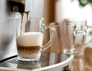 cappuccino coffee preparing in glass cup with help of machine