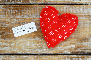 Miss you card with red heart on rustic wooden surface