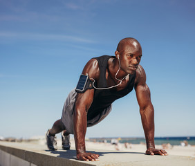 Muscular man doing push ups against blue sky