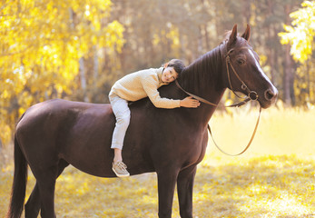 Autumn season happy teenager boy on the horse in the forest