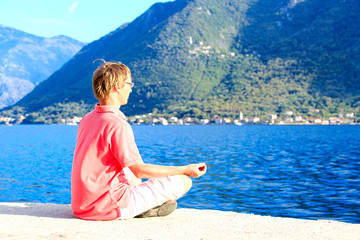 young man meditating at the beach