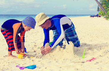 father and son building sand castle on beach