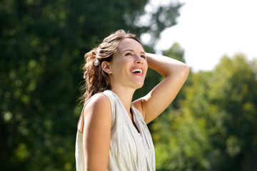 Naklejka premium Carefree woman smiling with hand in hair outdoors