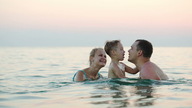 Happy family of three bathing in sea