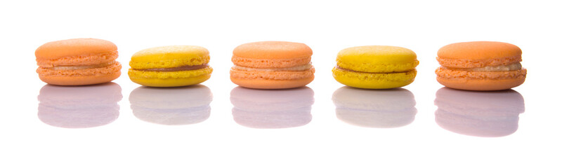 Yellow and orange colored French macarons on white background