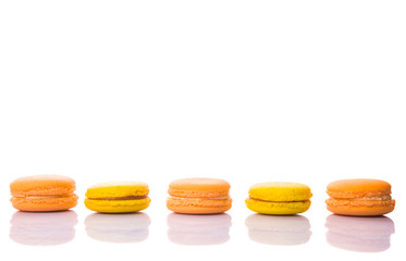 Yellow and orange colored French macarons on white background