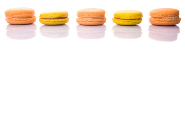 Yellow and orange colored French macarons on white background