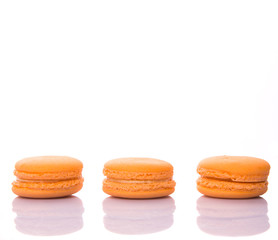 Orange colored French macarons over white background