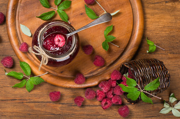 Top view of a jar of raspberry jam and  fresh berries