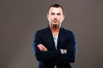 Portrait of a serious man with arms folded on gray background