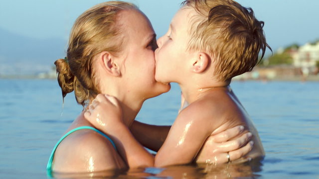Boy kissing and embracing mother in sea