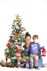 Fototapeta na wymiar Mother and their small child sits near Christmas tree with lamps