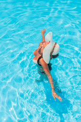 Woman with straw hat in the swimming pool