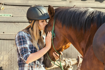 Beautiful young woman kissing her horse