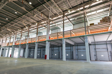 Big automated warehouse, panorama of mezzanine and loading gates or docks, industry concept - obrazy, fototapety, plakaty