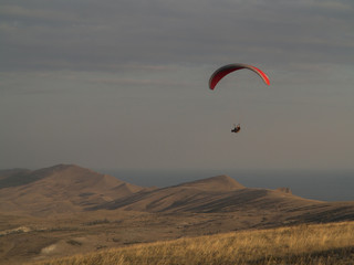 Fototapeta na wymiar Paragliding. Hang glider flying over mountains.