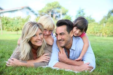 Fototapeta premium Family of four laying on grass in front of house