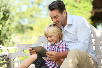 Daddy and son playing with tablet outside