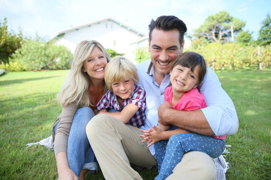 Portrait of happy family of four sitting in yard