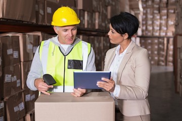 Warehouse worker scanning box with manager