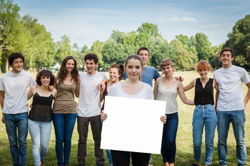 Gruppo di amici al parco.Una ragazza tiene un cartellone bianco