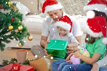 Family looking at the little boy opening a present