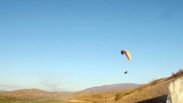 A paraglider soaring along a ridge line gains lift