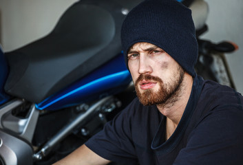 Portrait of Serious young man with his motorcycle on background